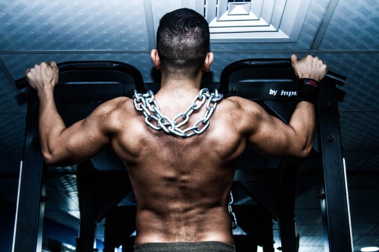 Strong man doing a pull up with back muscles showing