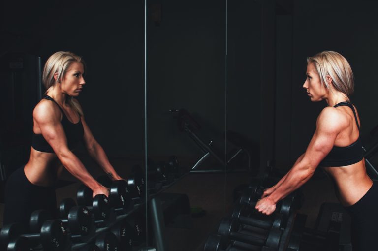 Strong woman looking at muscly physique in the mirror